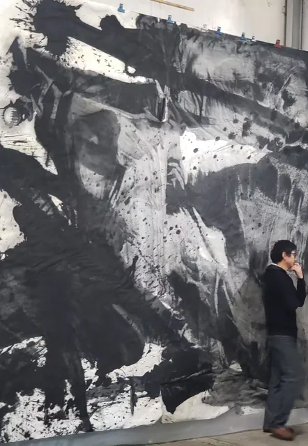 悬挂的大型黑白水墨作品与一位驻足人物