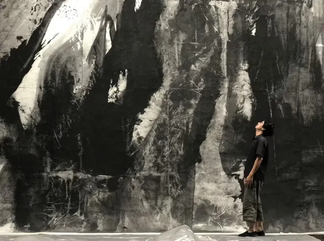 人物仰望大型水墨画面，体现画作的体量